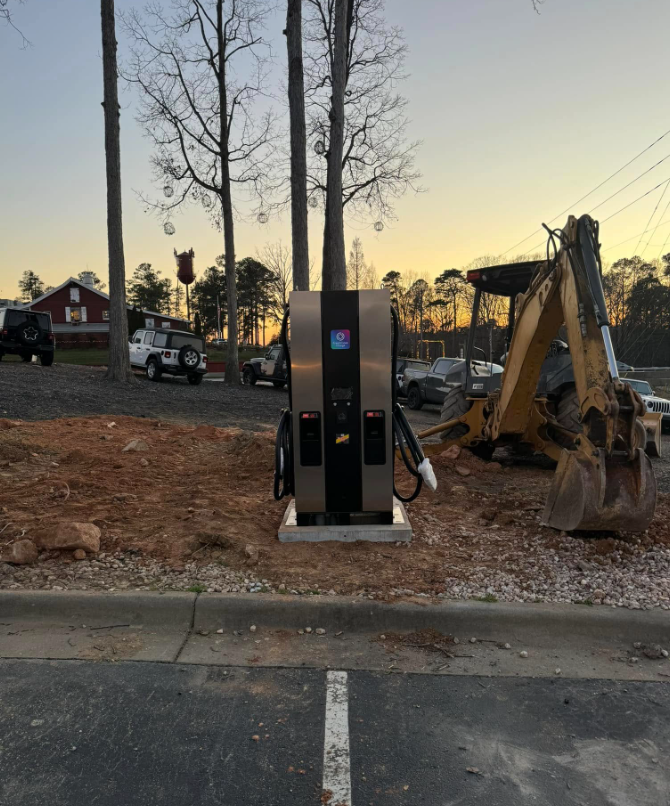 Commercial DC fast EV charger installed on a concrete pad at dusk